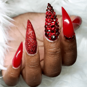 Stiletto nails with red glitter and crystals.