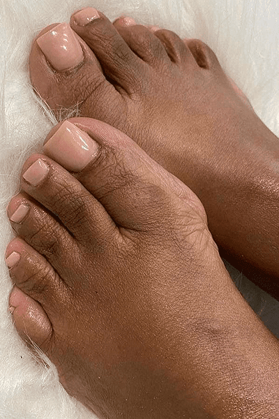 Close-up of light brown toes with a pink polish.